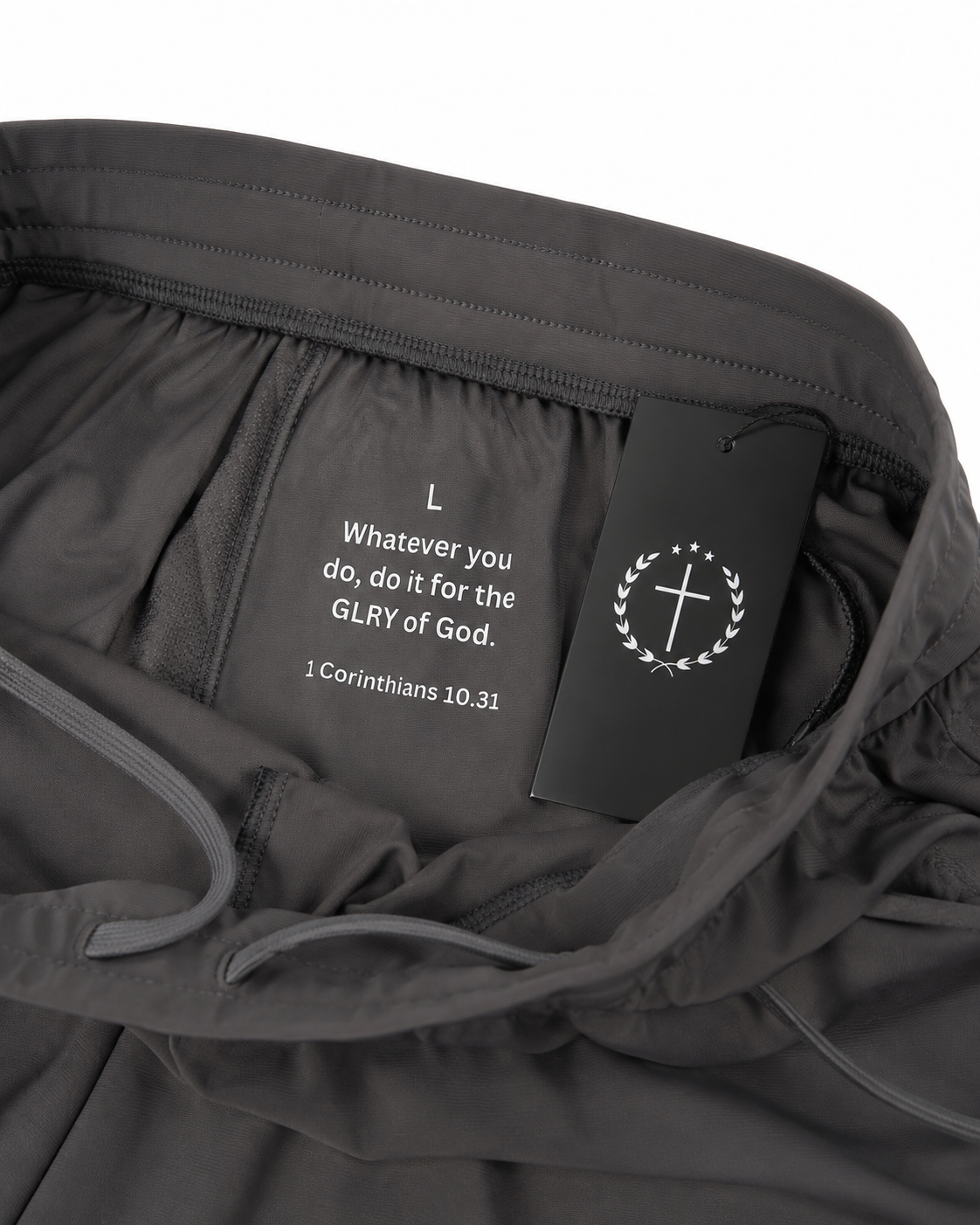 Gray joggers fabric closeup with inner tag, drawstring, and circular logo embroidery