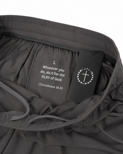 Gray joggers fabric closeup with inner tag, drawstring, and circular logo embroidery
